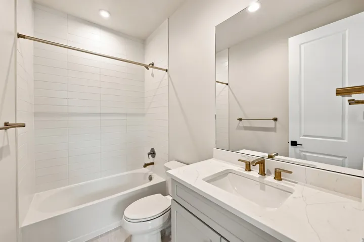 Bathroom featuring a white bathtub, toilet, and vanity with a rectangular sink