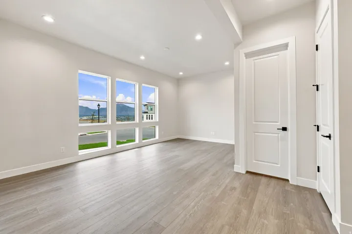 Recessed ceiling lighting, wood-finish flooring, multiple windows, white paneled doors, and matte black door hardware