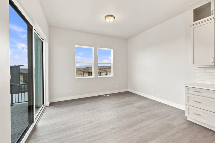 Light wood-finish flooring, white walls, and a sliding glass door leading to an outdoor deck
