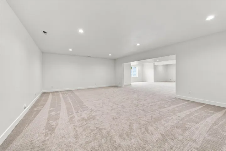 Expansive open-concept room featuring plush carpet, recessed lighting, and crisp white walls