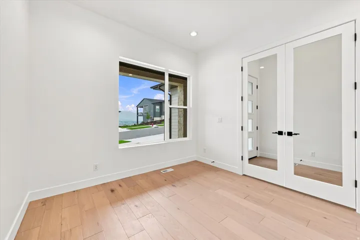 Light wood-finish flooring, white walls, and a large window with white trim
