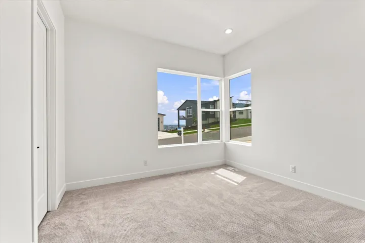 Corner window configuration with expansive glass panels, recessed ceiling lighting, light-toned carpeting, and a white interior door