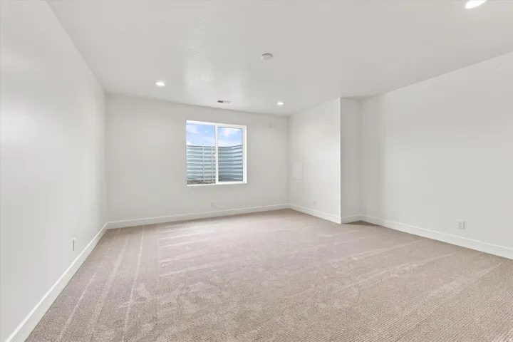 Recessed lighting, large window, neutral carpet, and white wall finishes