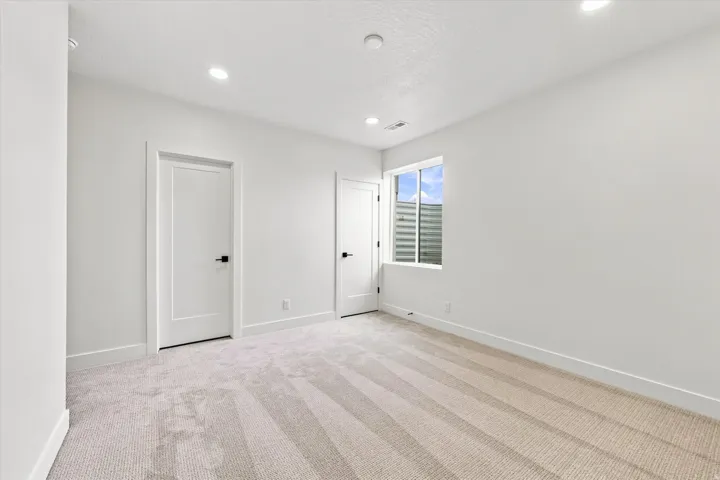 Plush carpeting, recessed lighting, and bright white walls
