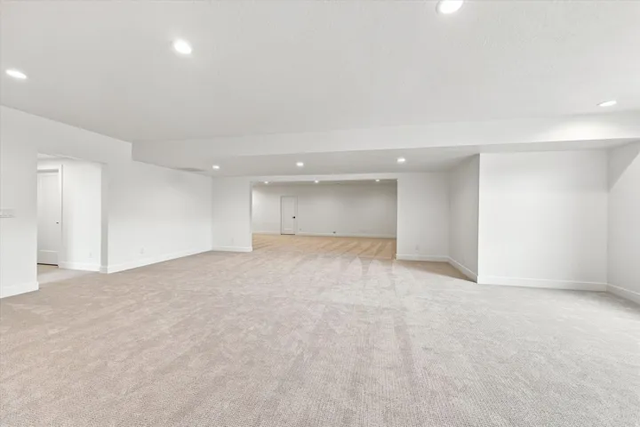 Expansive open-concept living space featuring recessed lighting, light-toned carpeting, and white walls