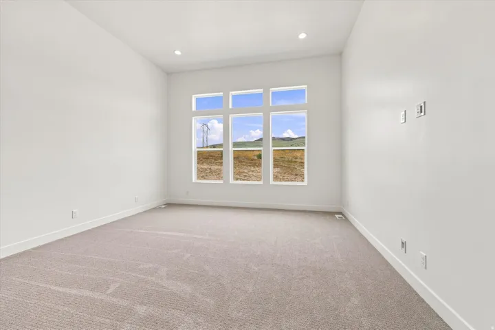 Expansive room featuring multiple vertical windows, recessed lighting, white walls, and light-colored carpeting