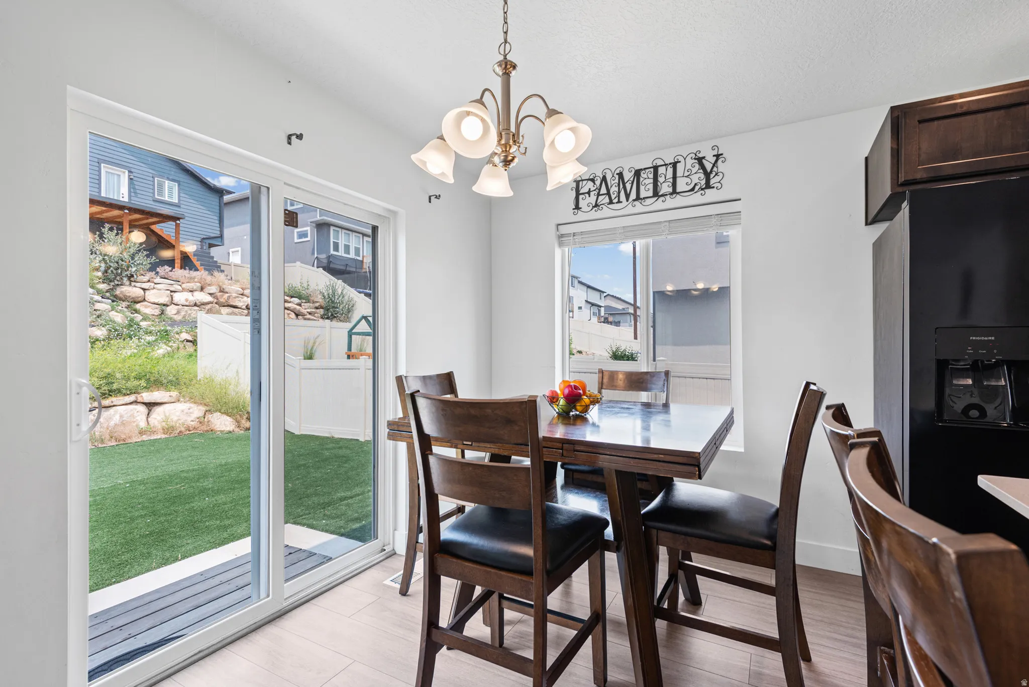 Dining area featuring wood-finish flooring, a contemporary ceiling light fixture, and a window providing natural light