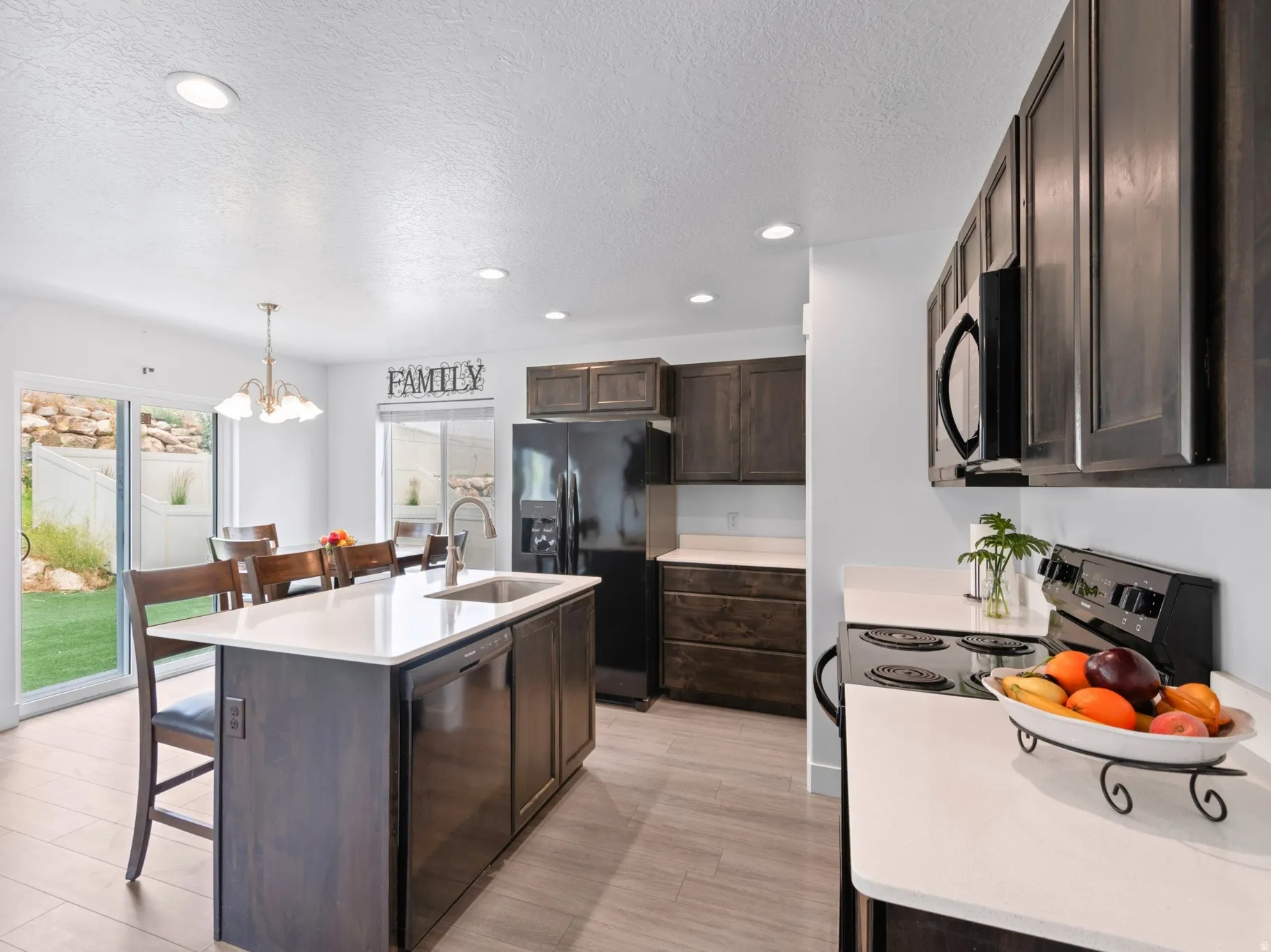 Modern kitchen featuring wood-finish cabinetry, light countertops, and stainless steel appliances