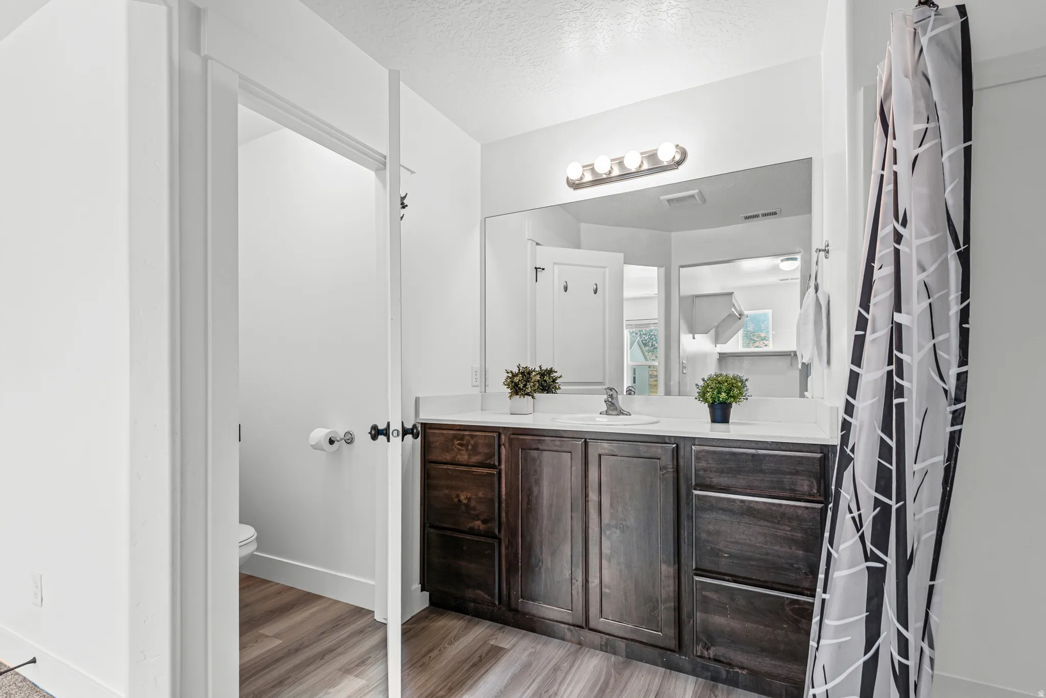 Bathroom featuring a dark wood-finish vanity with a light countertop, a built-in mirror, and overhead vanity lighting