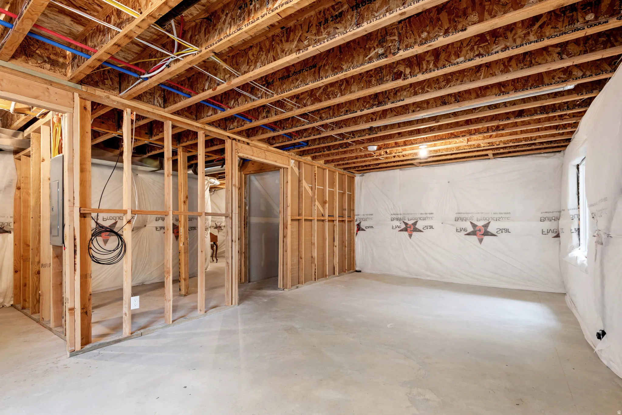 Unfinished basement featuring exposed wood framing, concrete flooring, and an open wood joist ceiling