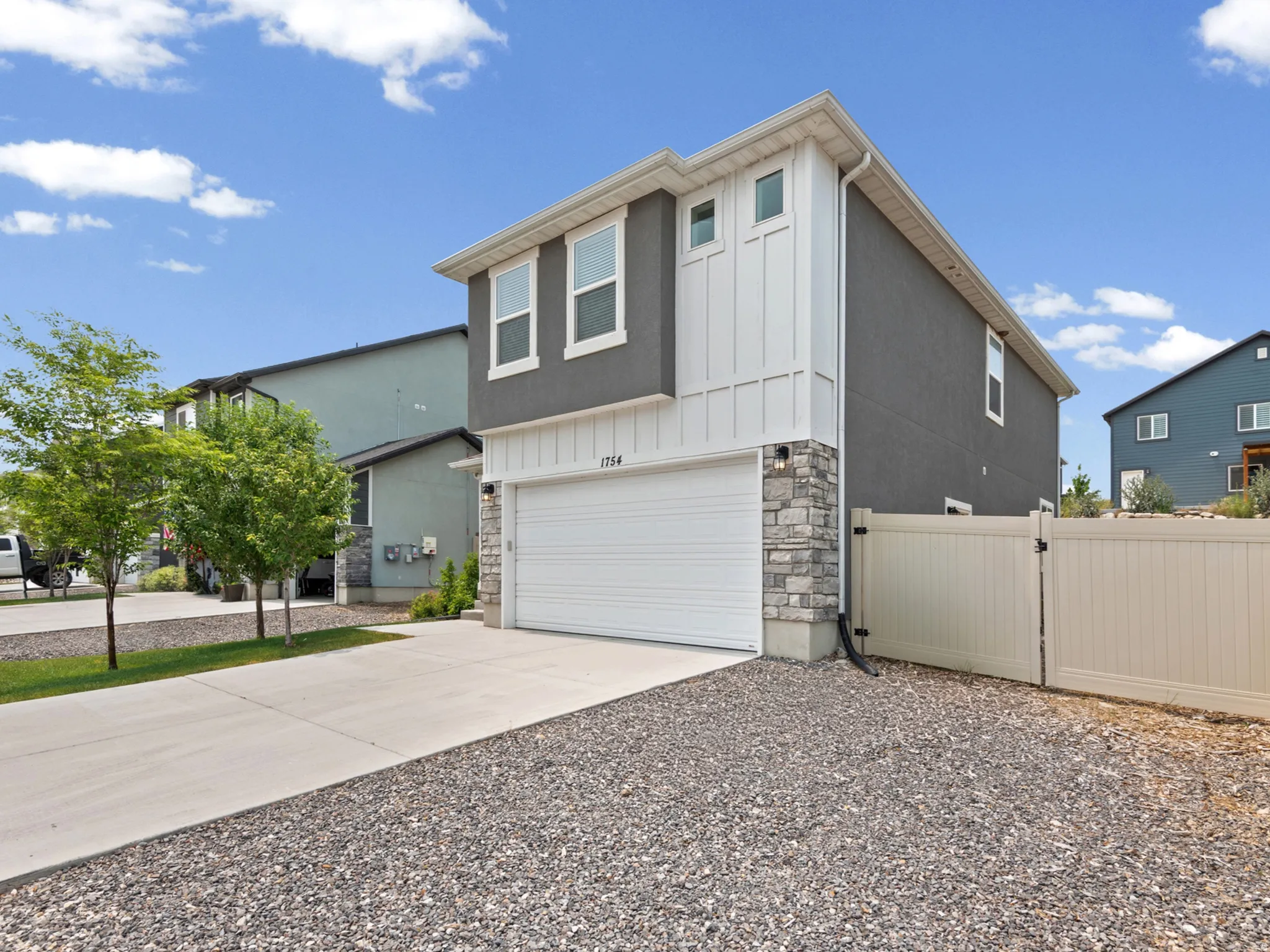Modern two-story exterior with a two-car garage, stone accent siding, and vertical board and batten detailing