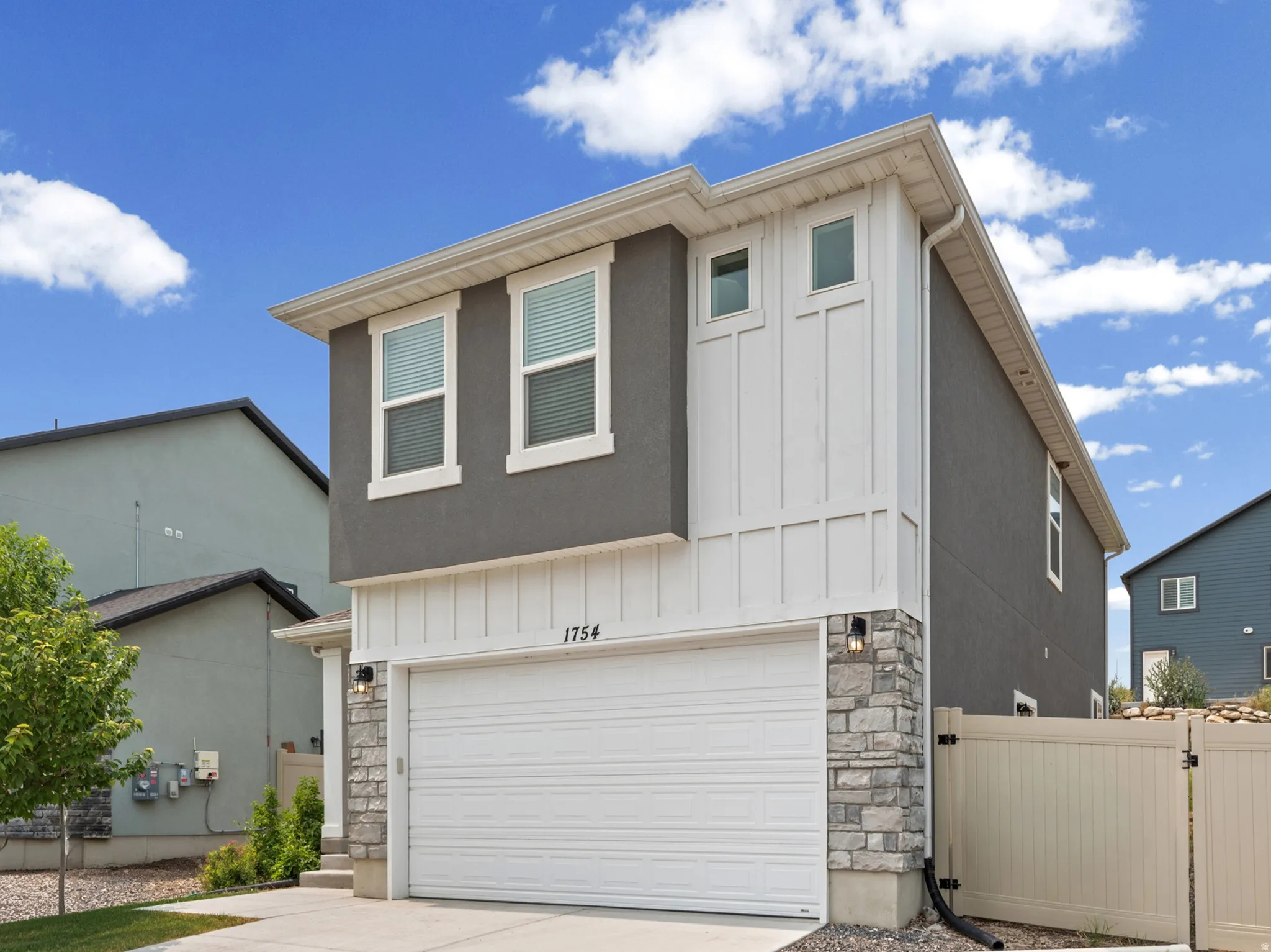 Contemporary two-story residence featuring a two-tone facade with dark gray stucco and white board and batten siding