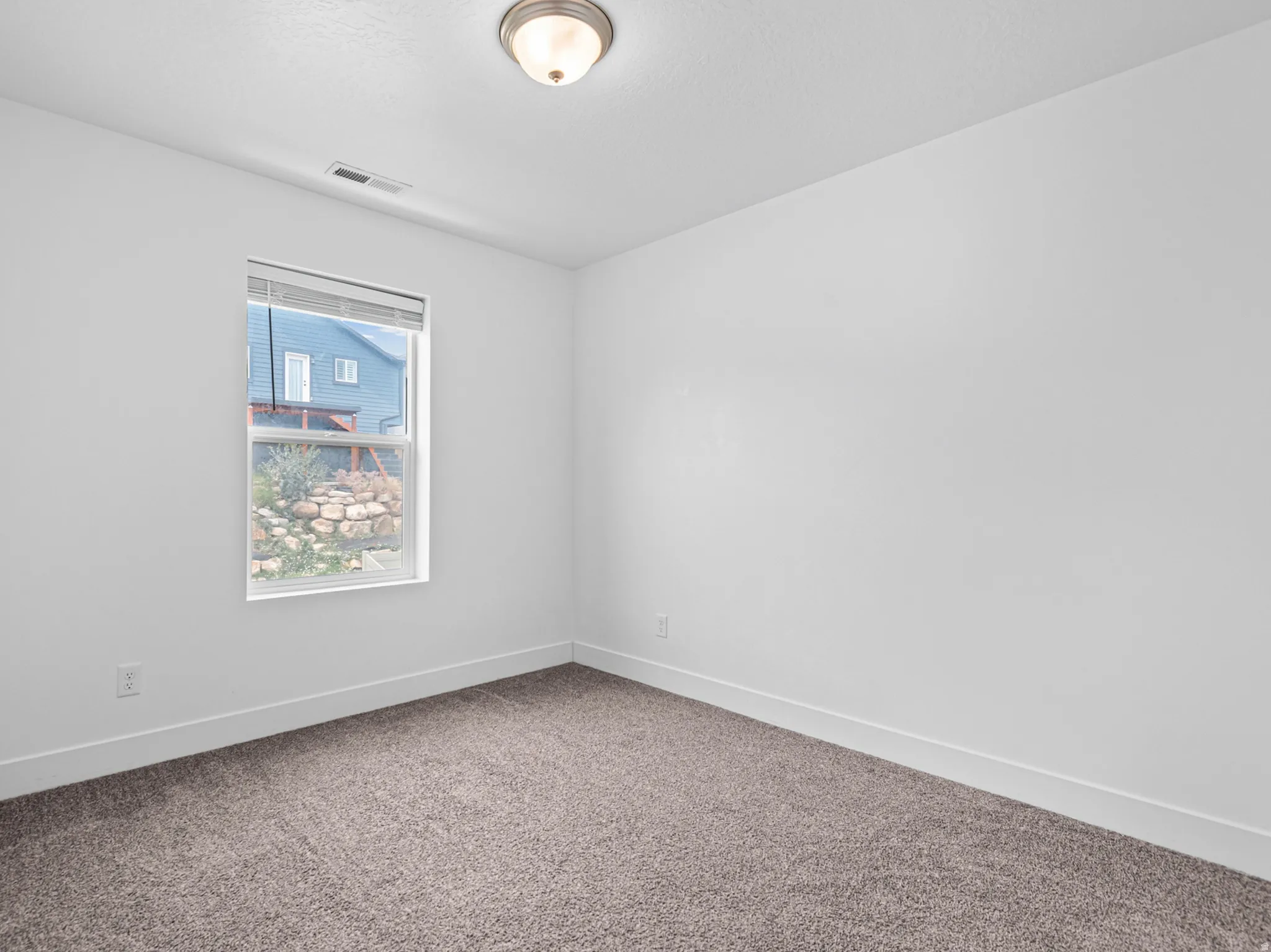 Room featuring neutral carpeting, white walls, a single window, and a flush-mount ceiling light fixture