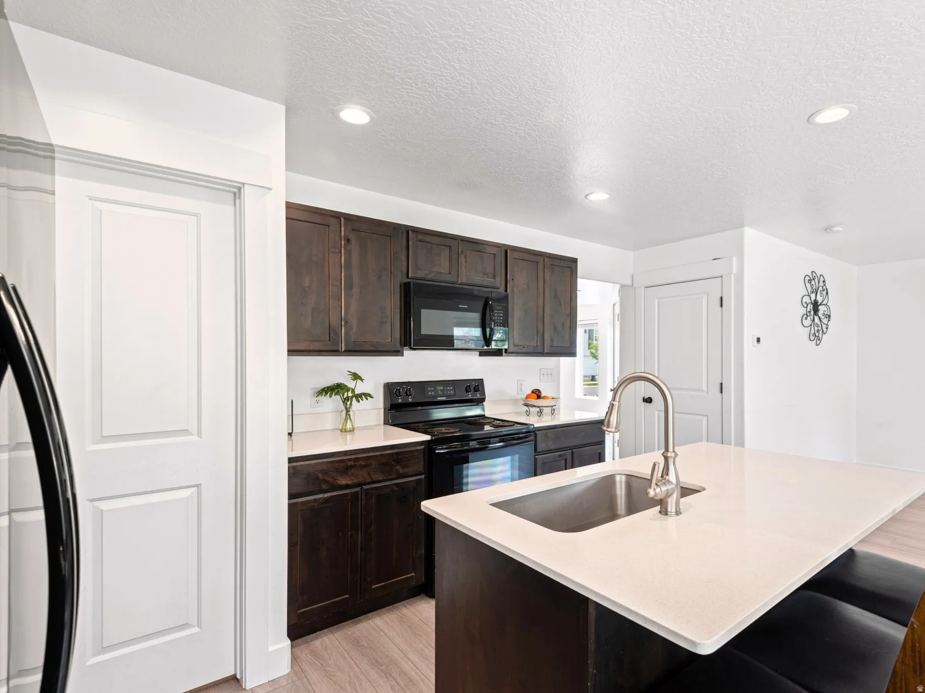 Kitchen featuring dark wood cabinetry, a central island with an undermount sink and gooseneck faucet