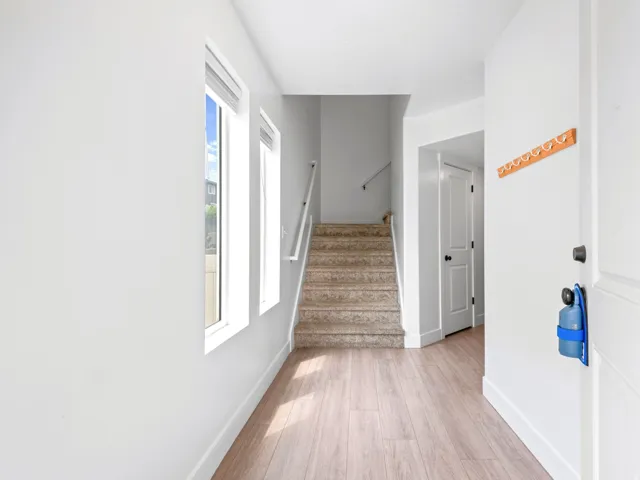 Inviting entryway featuring light wood-finish flooring, a white paneled door, and bright windows