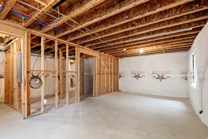 Unfinished basement featuring exposed wood framing, concrete flooring, and an open wood joist ceiling