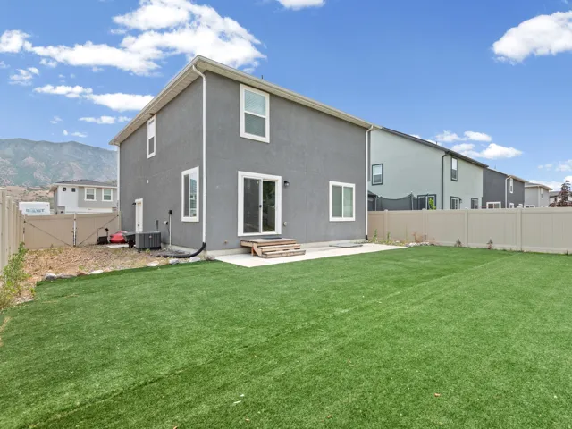 Expansive artificial turf backyard featuring a concrete patio pad and a full privacy fence