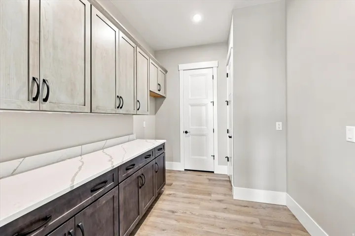 Extensive cabinetry with two-tone finishes, white countertop, wood-finish flooring, and recessed ceiling lighting