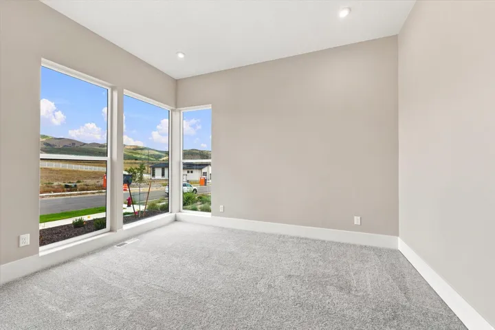 Expansive windows, neutral wall tones, recessed lighting, and soft gray carpeting