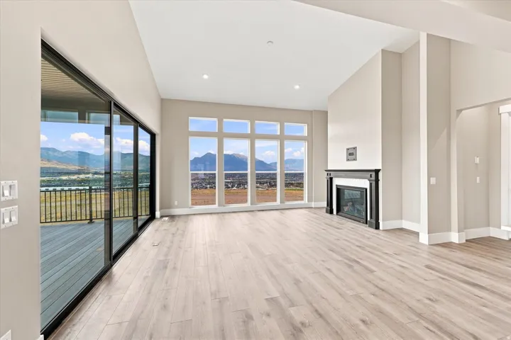 Spacious living area featuring large windows, wood-finish flooring, a built-in fireplace with a dark mantel, recessed lighting, and access to an outdoor deck