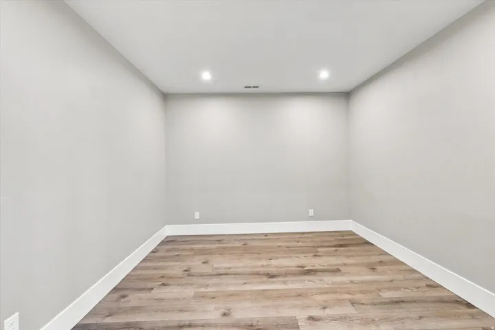 Recessed lighting, light gray wall finish, wood-finish flooring, and white trim