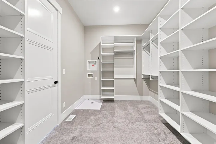 Expansive walk-in closet featuring built-in shelving, hanging rods, and plush carpeting
