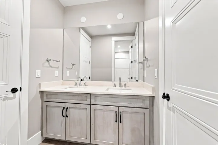 Dual vanity with light-toned cabinetry, an integrated mirror, and chrome fixtures