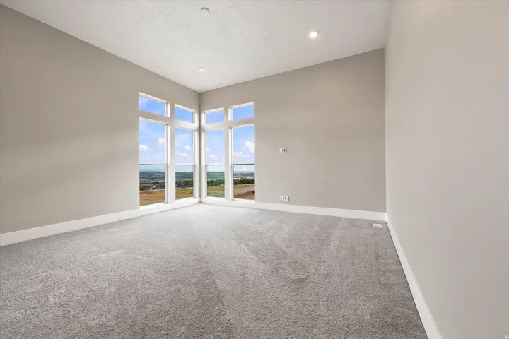 Expansive room with neutral gray walls, recessed lighting, and a corner window arrangement
