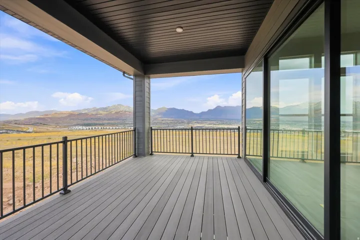 Covered outdoor patio with composite decking, black metal railing, and large sliding glass doors