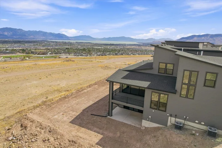 Contemporary architecture featuring an expansive upper-level balcony, a lower-level patio, and multiple large windows
