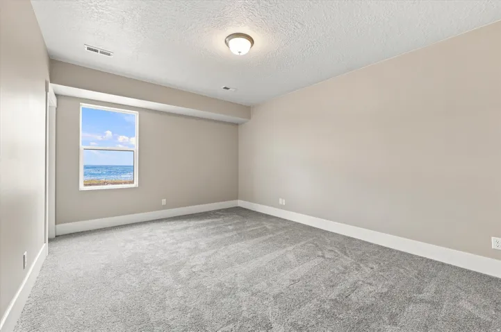 Plush grey carpeting, neutral wall finishes, and a single window offering a clear ocean backdrop