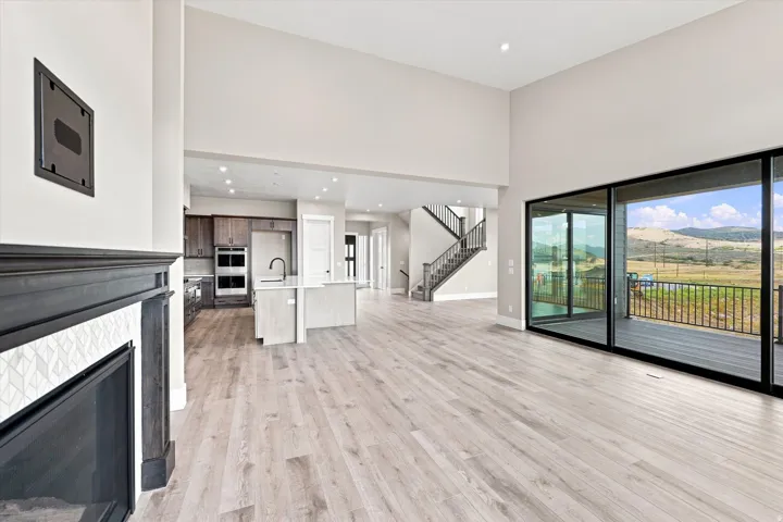 Open-concept living space with high ceilings, wood-finish flooring, and a fireplace with a decorative tile surround