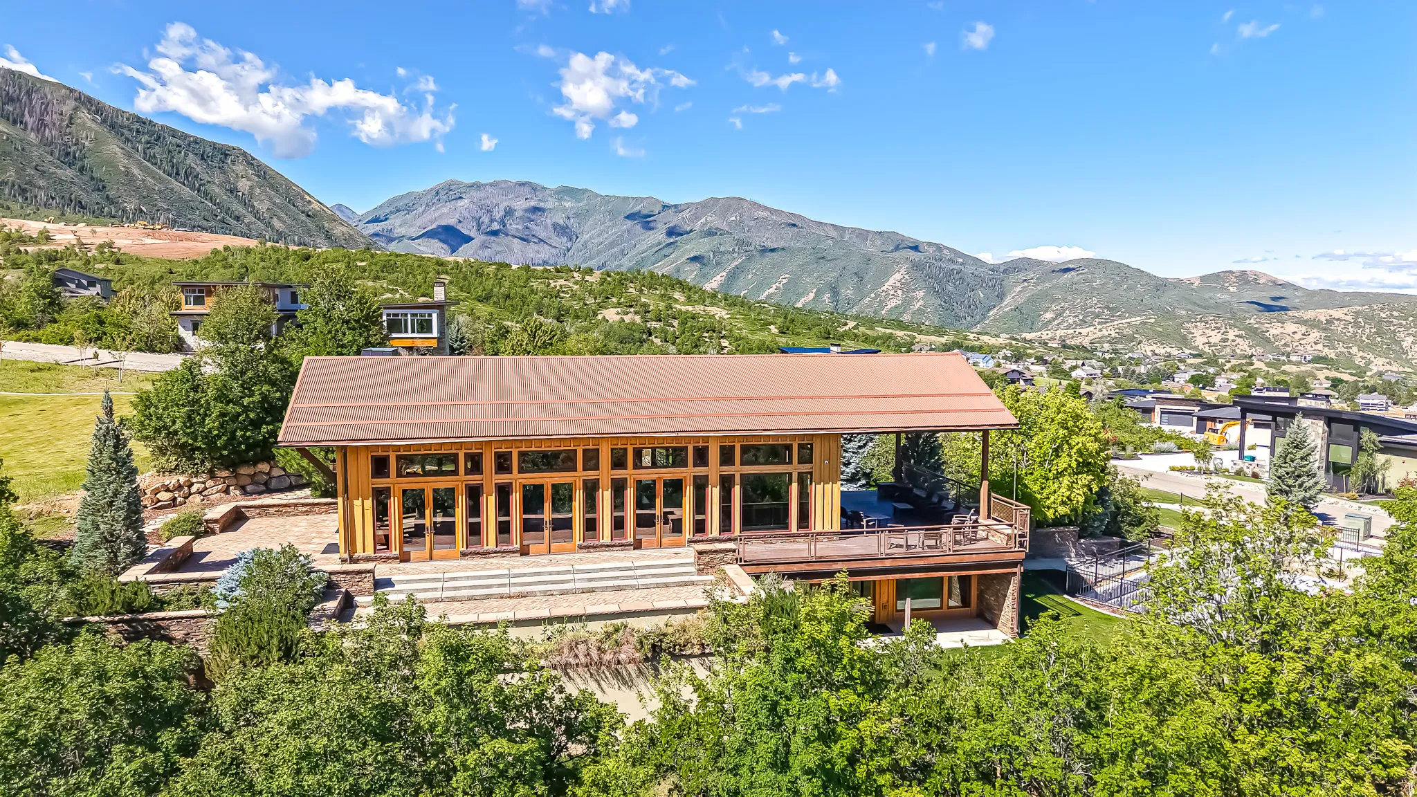 Mountain-side residence featuring a metal roof and expansive window-lined facade