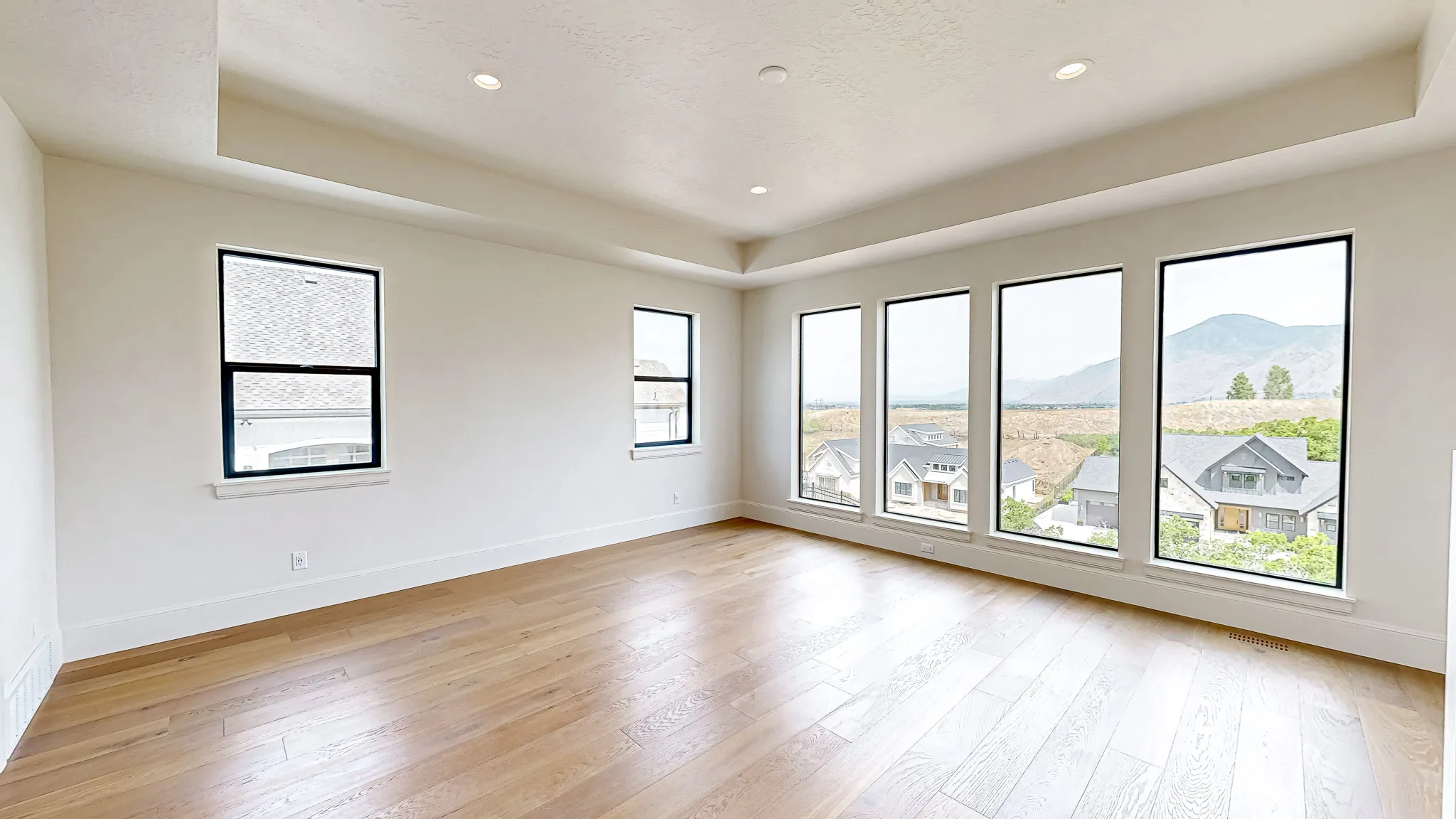 Spacious room featuring wood-finish flooring, recessed lighting, and a tray ceiling