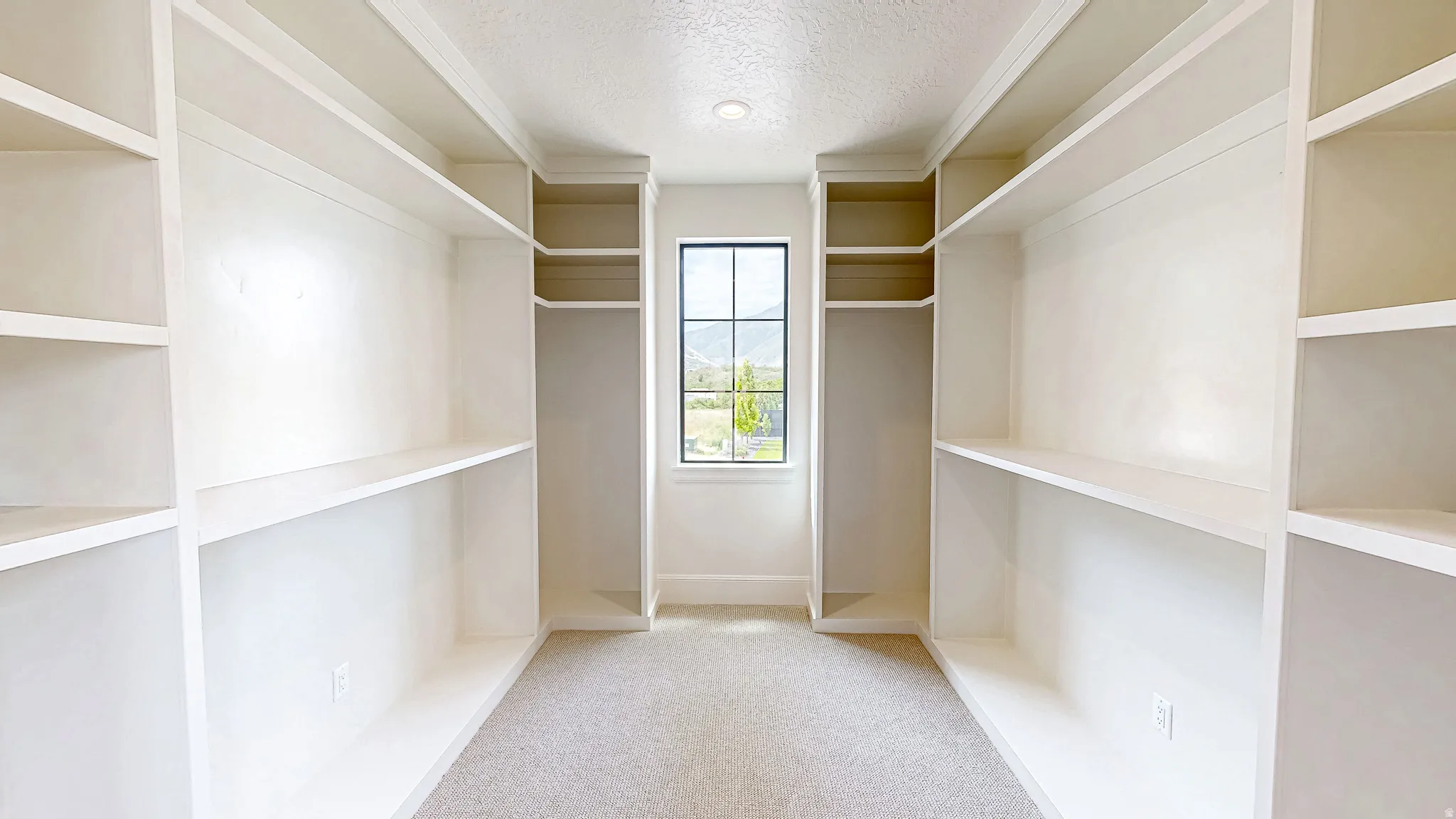Walk-in closet featuring extensive built-in shelving, hanging rods, recessed lighting, and a centered window