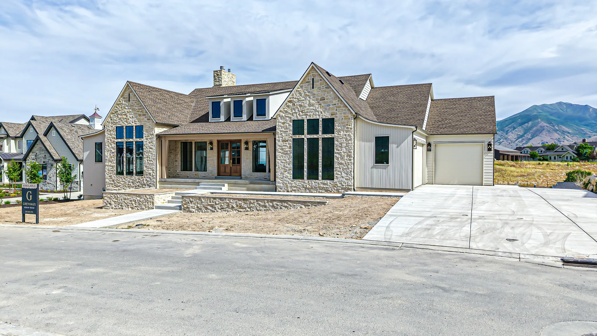 Stone and siding exterior with a covered front porch featuring a wood entry door and multiple dormer windows