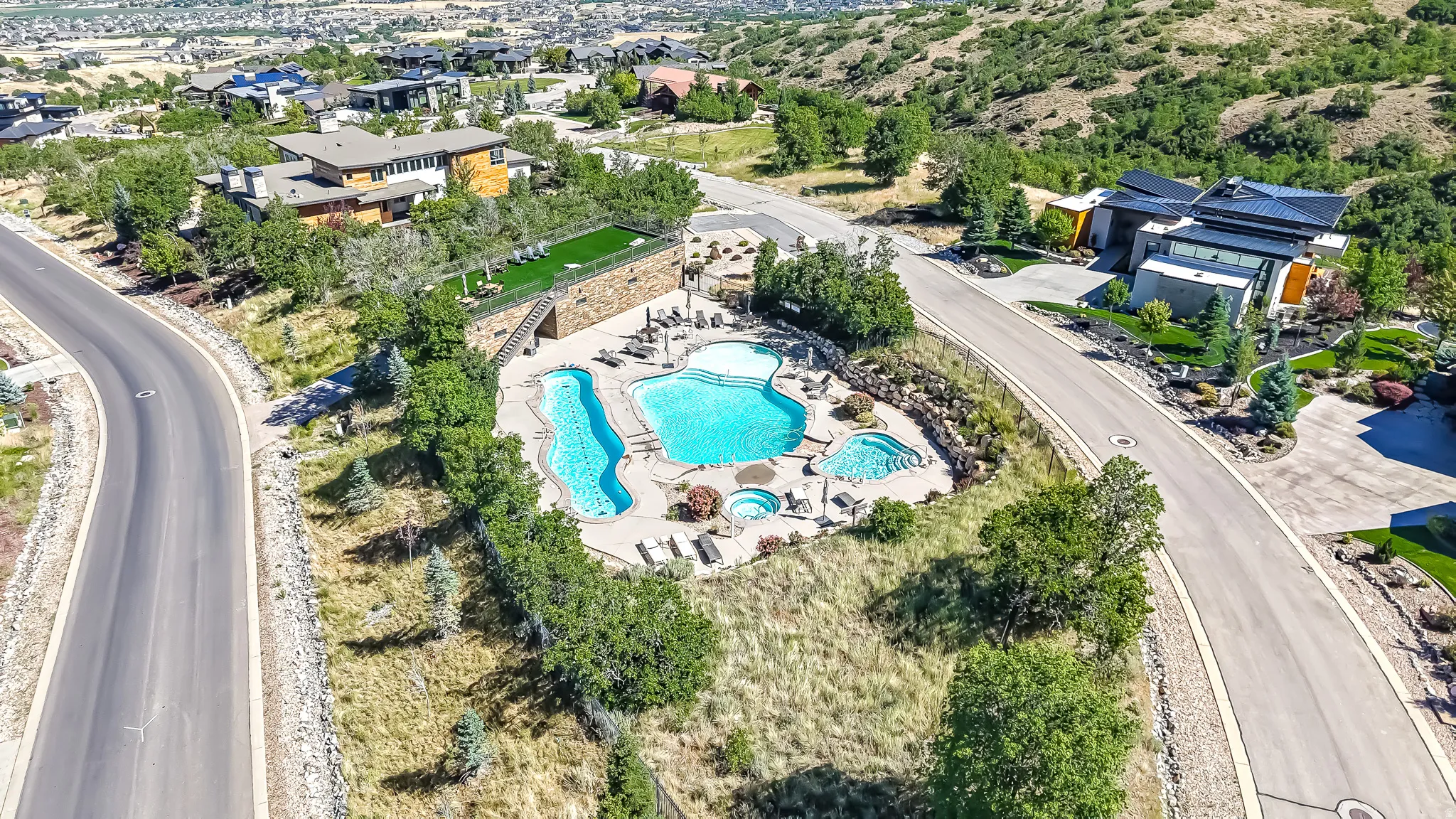 Community pool area featuring multiple swimming pools, two hot tubs, and a stone-clad retaining wall