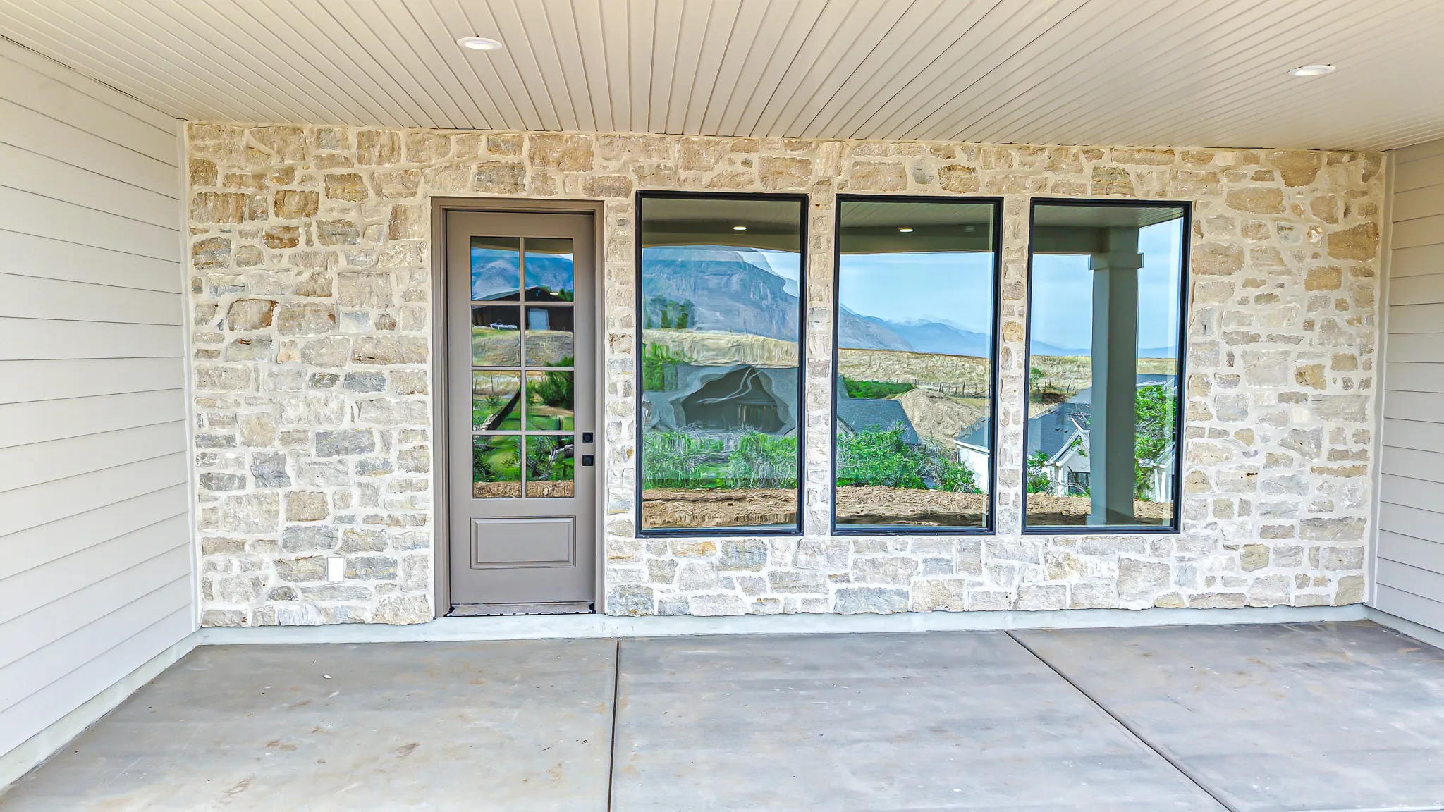 Covered patio with a concrete floor, stone veneer exterior, and horizontal siding