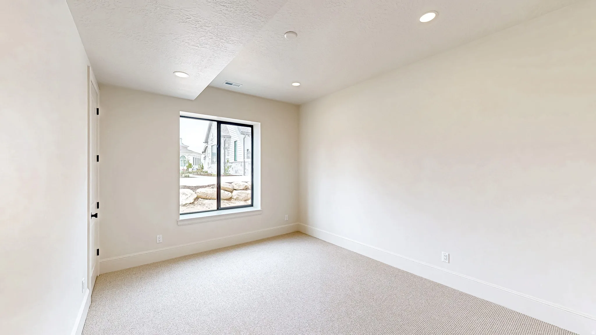Bright room with neutral carpeting, recessed lighting, and a large egress window