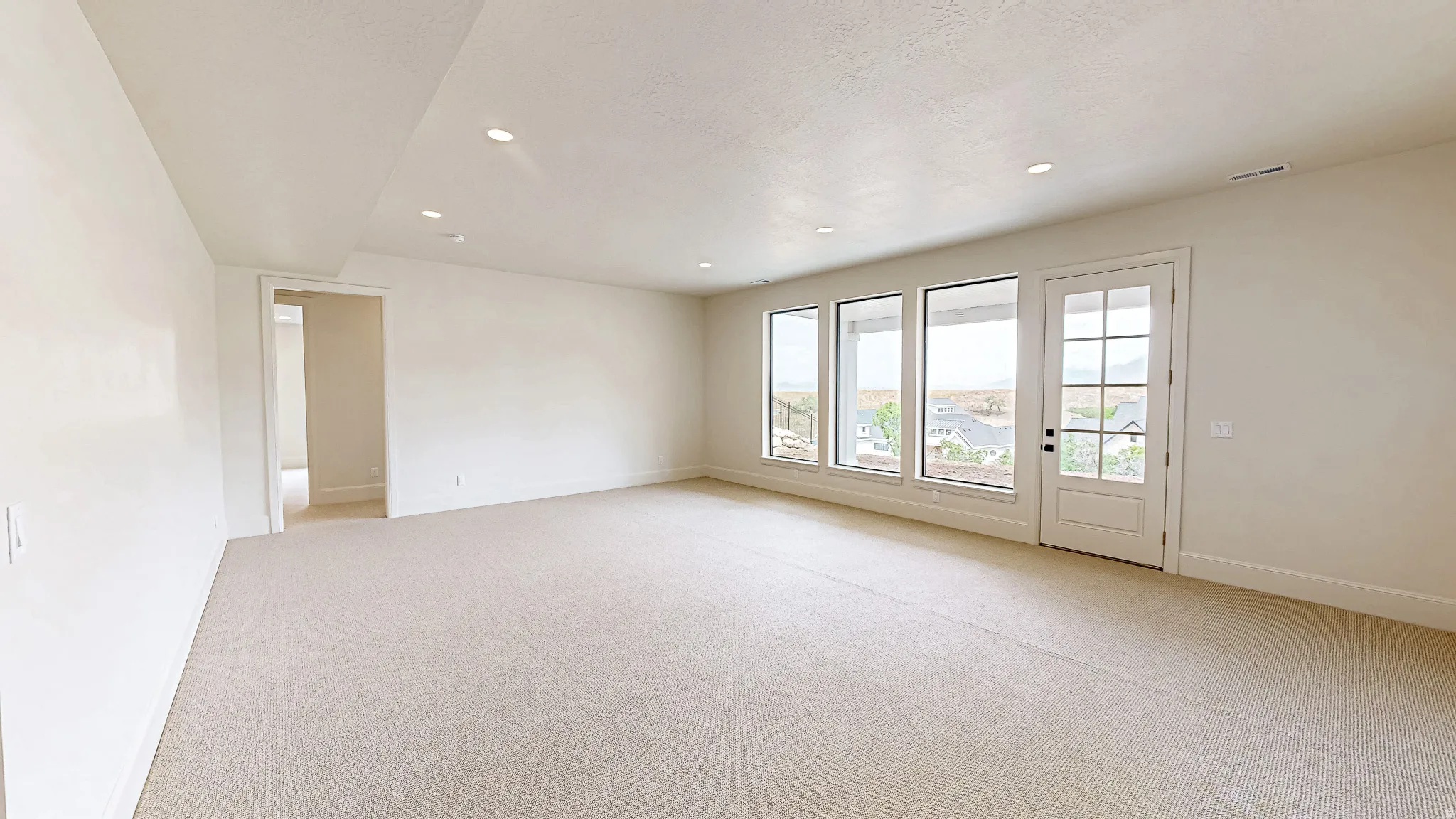 Spacious interior room with light-toned carpeting and recessed ceiling lighting