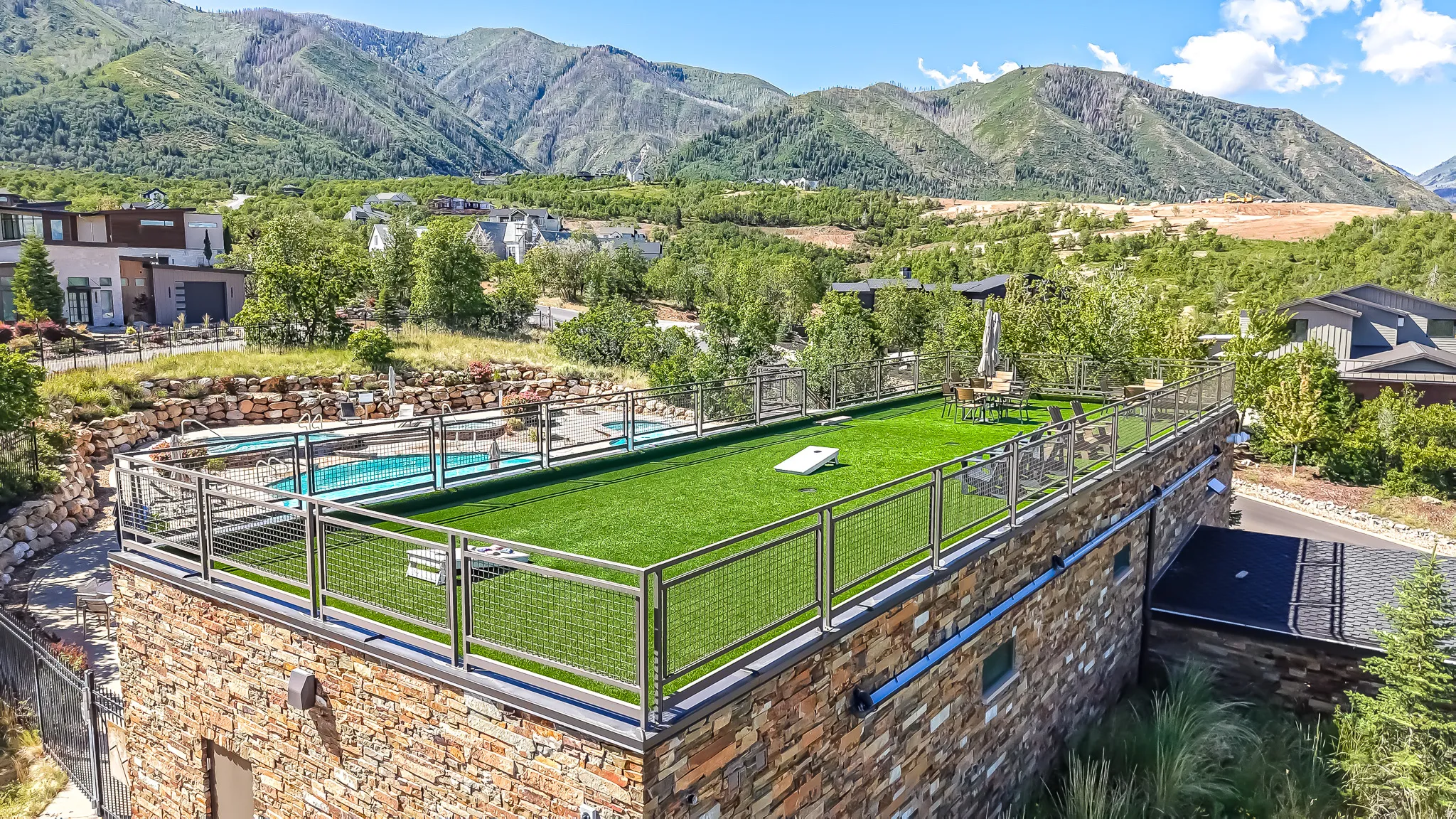 Rooftop turf-covered patio with metal railing overlooking a mountain landscape