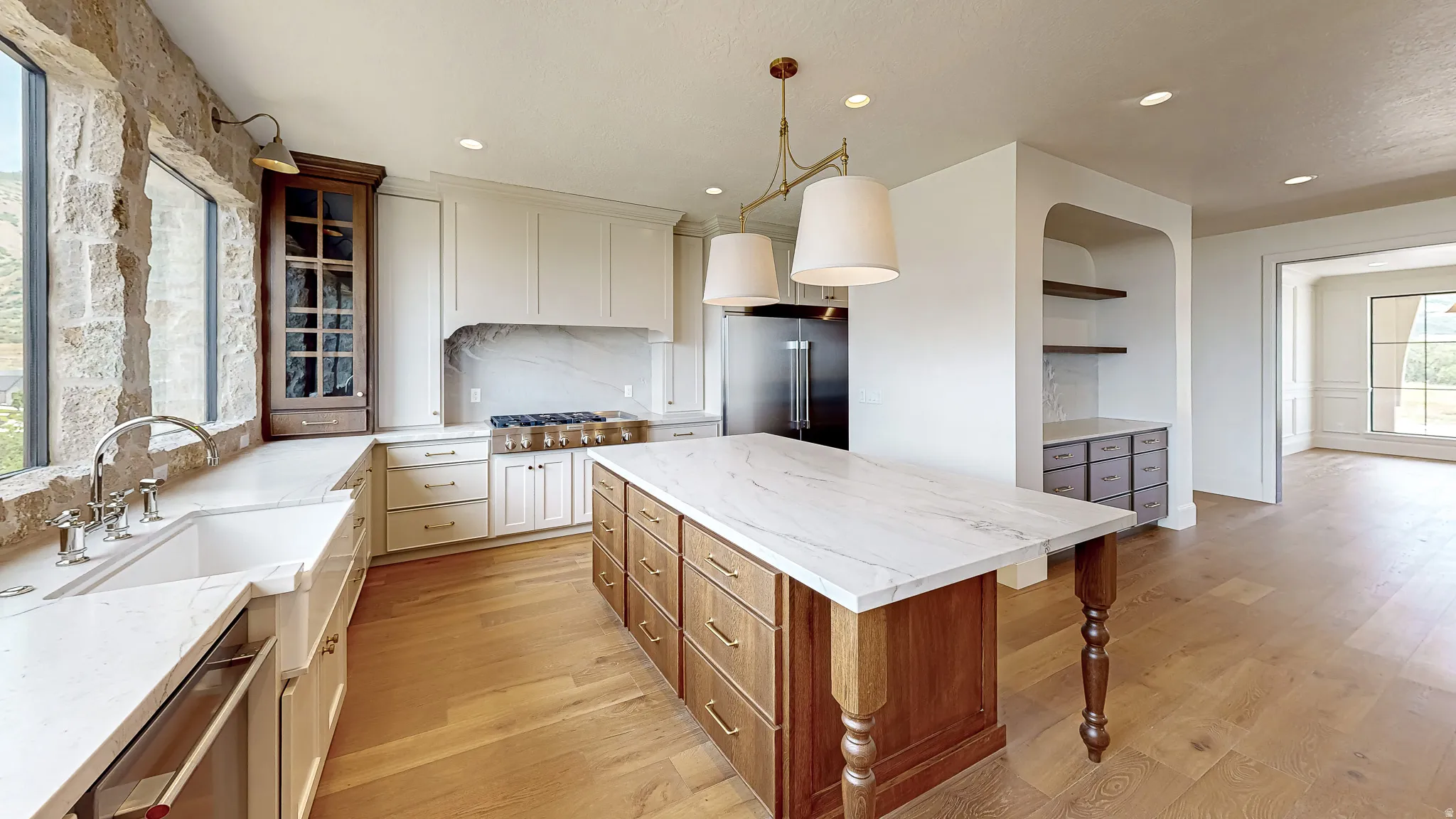 Gourmet kitchen featuring a substantial central island with a stone countertop, white cabinetry with a stone backsplash, a professional-grade range, integrated refrigerator, and wood-finish flooring