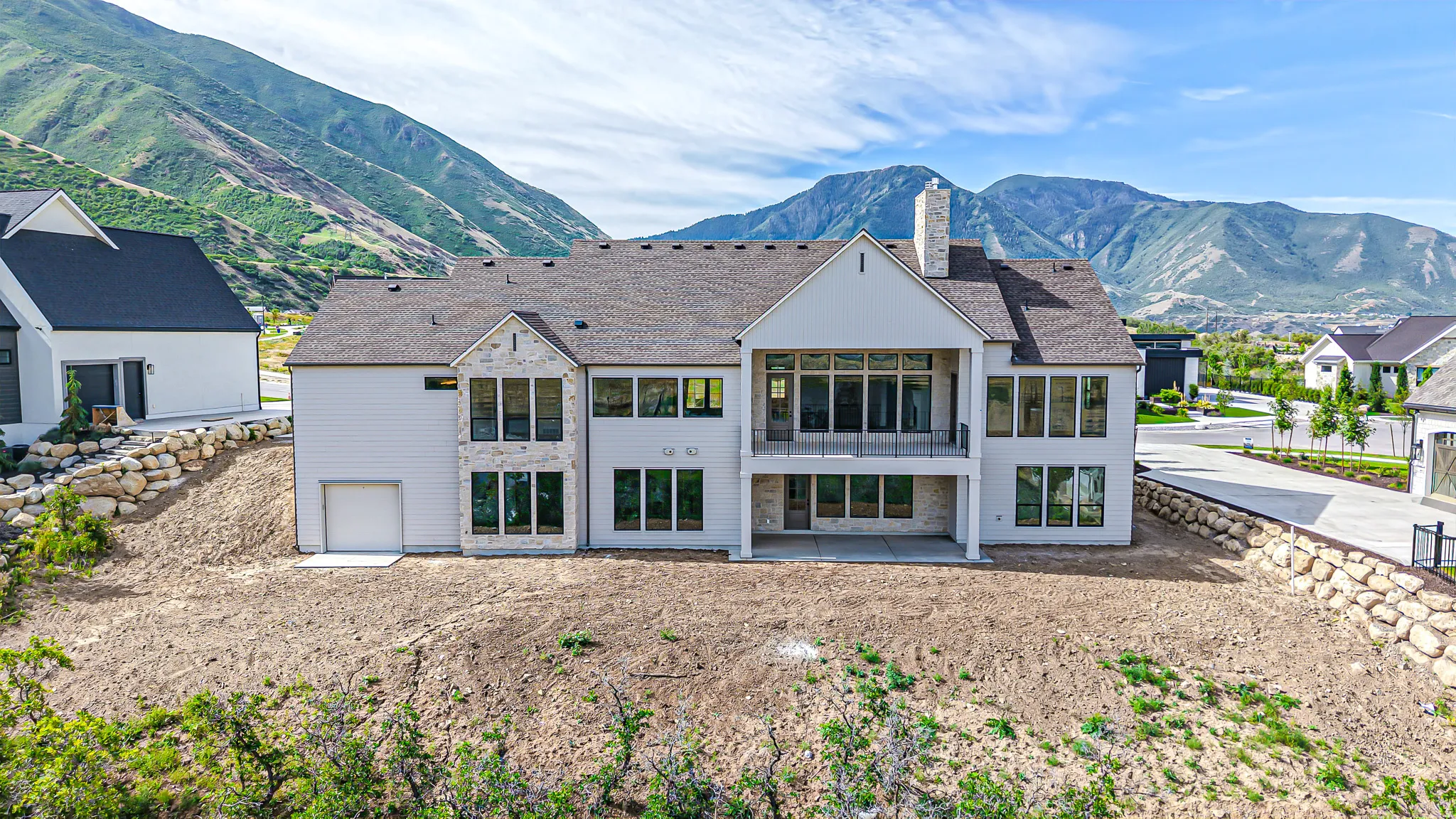 Newly constructed residence featuring a light-colored exterior with stone accents and a dark shingle roof
