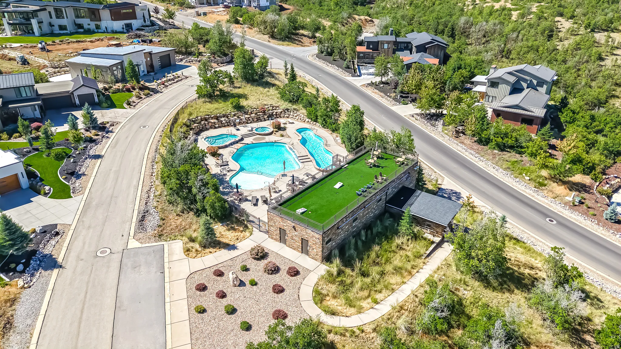 Expansive outdoor aquatic area featuring a large freeform swimming pool, two integrated spas, and a surrounding stone patio