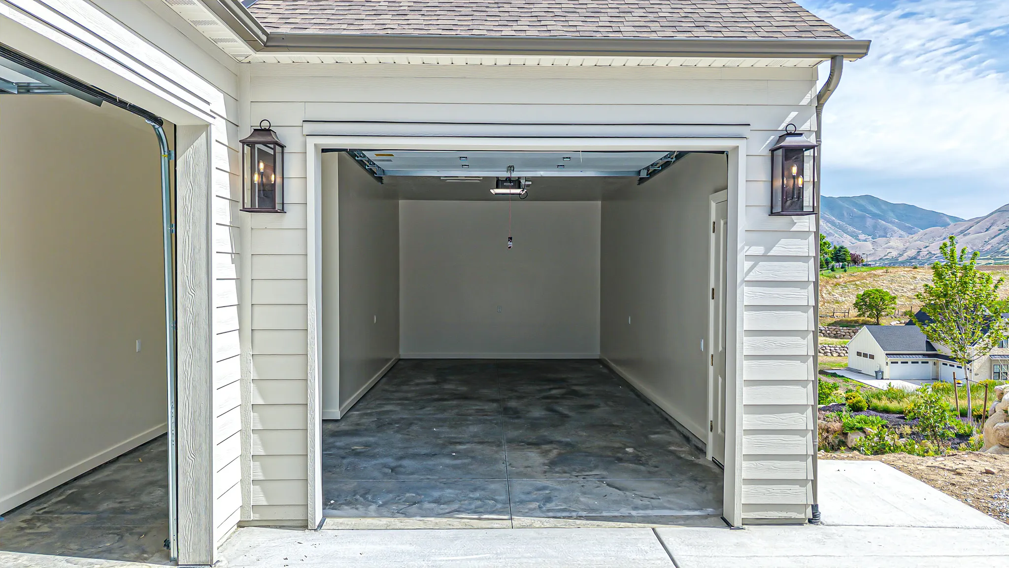Two-car garage featuring a concrete floor, light-toned painted walls, and overhead garage door mechanisms