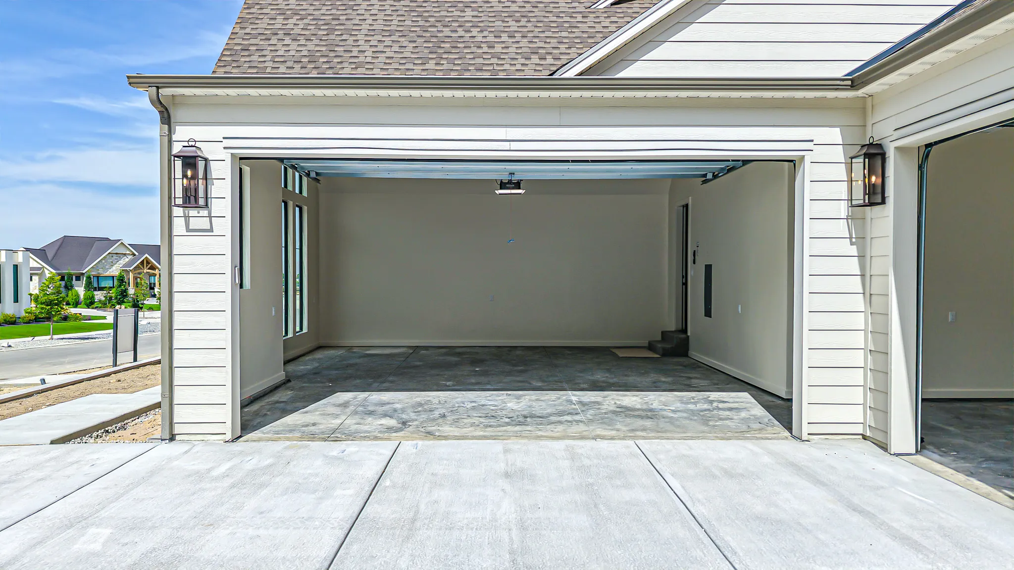 Two-car garage with concrete flooring, side-mounted exterior lanterns, and a dedicated side entrance