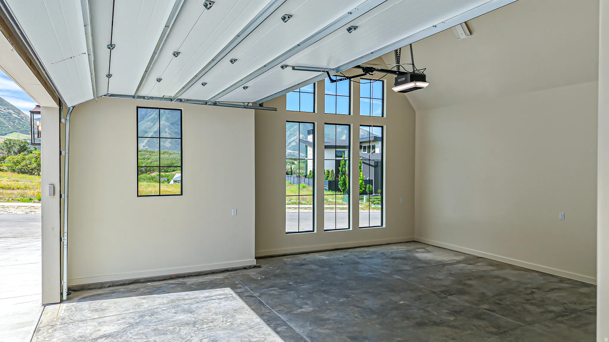 Spacious garage with an automatic overhead door, concrete flooring, and multiple multi-pane windows providing natural light
