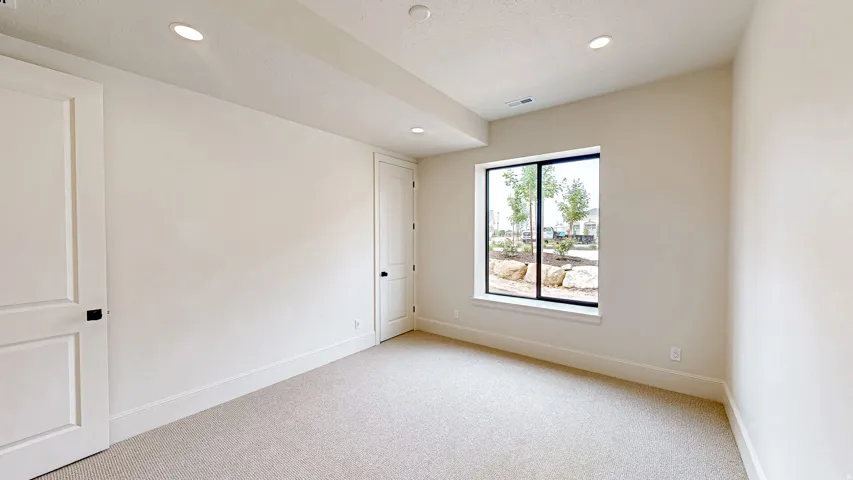 Carpeted room featuring recessed lighting, a large picture window with black trim, and two paneled doors with black hardware
