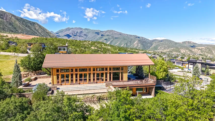 Mountain-side residence featuring a metal roof and expansive window-lined facade