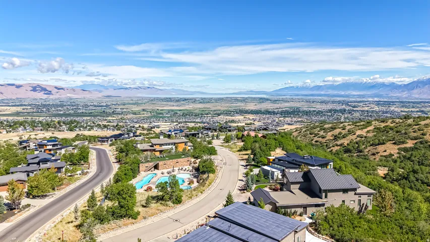 Hillside residential community featuring contemporary homes with dark-toned roofs and a community swimming pool area